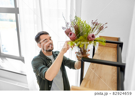 man decorating home with flowers in vase 82924659