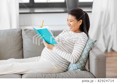 happy pregnant woman writing to diary at home happy pregnant woman writing to diary at home 82924714
