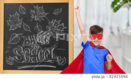 boy in super hero costume over school blackboard 82925098