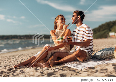 happy couple with food having picnic on beach 82925334