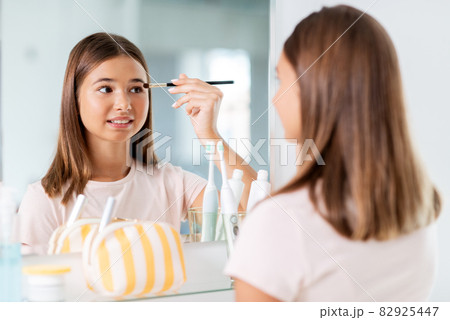 teenage girl applying eye shadow at bathroom teenage girl applying eye shadow at bathroom 82925447