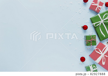 Christmas and New Year blue flat lay with various red, white and green present gift boxes top view. Gift ribbon and packaging paper. Decorating snow flakes, toy balls. Copy space text area on photo 82927888