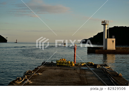 島根県隠岐郡隠岐島町　西郷港と隠岐島町漁港　隠岐の海　夕陽に照らされる桟橋と白い燈台　赤く染まる空 82929506