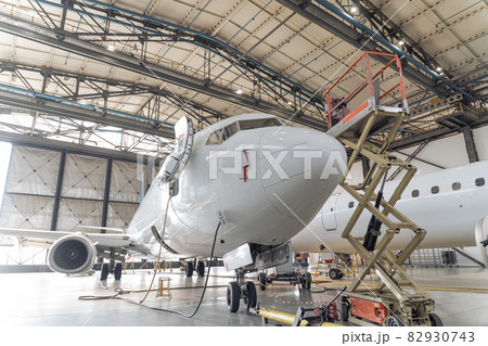 Big white plane in hangar during repair 82930743