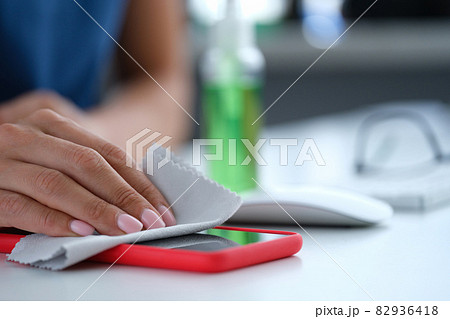 Woman hand wiping screen of mobile phone with antiseptic napkin closeup 82936418
