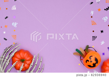 Halloween background with skeleton hands hold a pumpkin and candy bucket.  82936940
