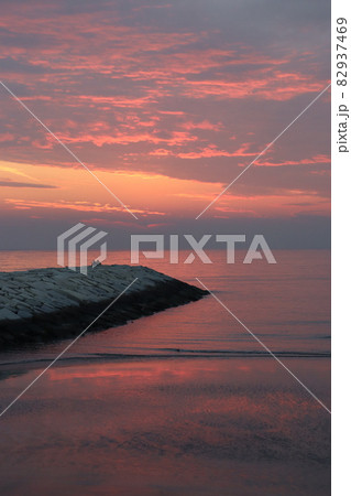 ピンクの夕焼けと海を眺めるカップル 82937469