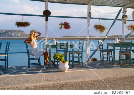 Young woman tourist in straw hat sitting at cafe at Ermioni marina, Greece 82939464