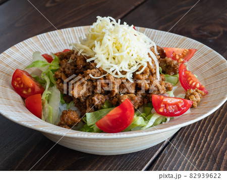 沖縄料理のタコライス。スパイシーに炒めた挽き肉とレタスとトマトとチーズをご飯のトッピングした料理。 沖縄料理のタコライス。スパイシーに炒めた挽き肉とレタスとトマトとチーズをご飯のトッピングした料理。 82939622