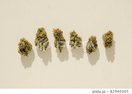 Marijuana buds lay in row on ivory table, top view, close-up. Cannabis dried flowers. 82940305