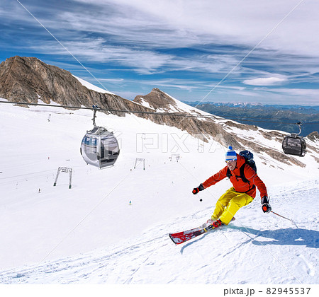 Skier skiing downhill during sunny day in high mountains, Kaprun glacier- Zell am see, Austria Skier skiing downhill during sunny day in high mountains, Kaprun glacier- Zell am see, Austria 82945537