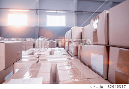 Warehouse with cardboard boxes in storage. The sunset shines through the windows, background Warehouse with cardboard boxes in storage. The sunset shines through the windows, background 82946357