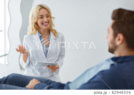 Smiling woman dentist having conversation with male patient 82946359