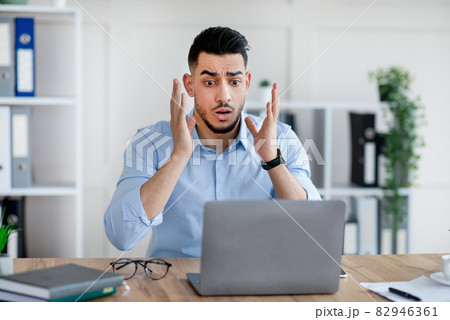 Stressed Arab businessman with laptop making mistake in work project, cannot meet deadline, feeling terrified in office 82946361