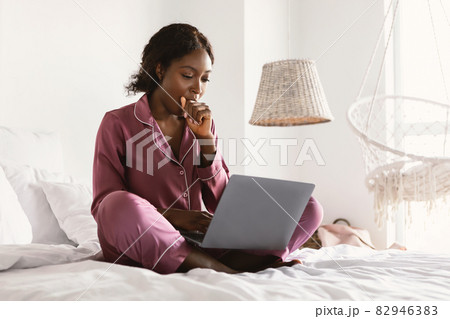 Sleepy African Freelancer Lady Using Laptop And Yawning In Bedroom Sleepy African Freelancer Lady Using Laptop And Yawning In Bedroom 82946383