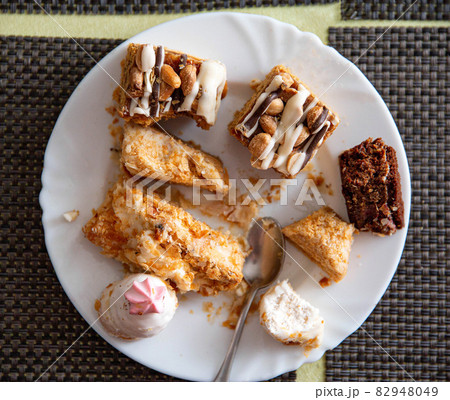 Leftovers in a plate on the table with sweets cakes, close-up Leftovers in a plate on the table with sweets cakes, close-up 82948049