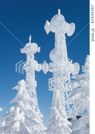長野県下高井郡山ノ内町にあると冬期横手山渋峠スキー場の山頂の青空と樹氷とアンテナの電波塔の景色 82948367