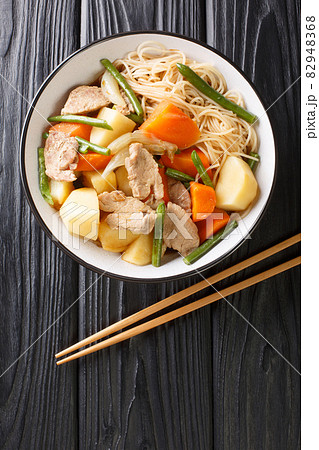 Nikujaga Recipe Pork and Potatoes Stewed in Savory Soy Sauce Based Dashi Broth close up in bowl. Vertical top view Nikujaga Recipe Pork and Potatoes Stewed in Savory Soy Sauce Based Dashi Broth close up in bowl. Vertical top view 82948368