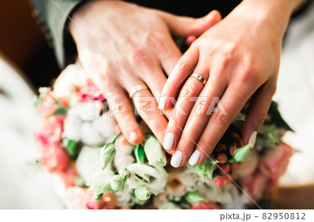 Beautiful young wedding couple posing with bouquet of flowers in hands Beautiful young wedding couple posing with bouquet of flowers in hands 82950812