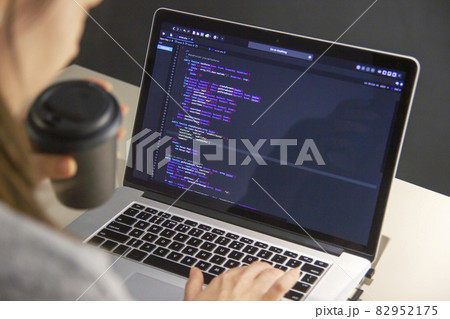 A programmer coding on a laptop in the workplace 82952175