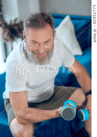 A man exercising with dumbbells and looking involved 82952774