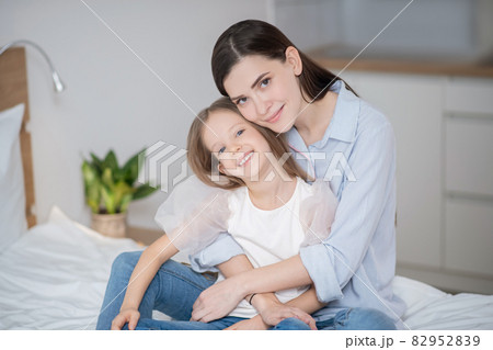 A pretty woman hugging her daughter and looking happy 82952839