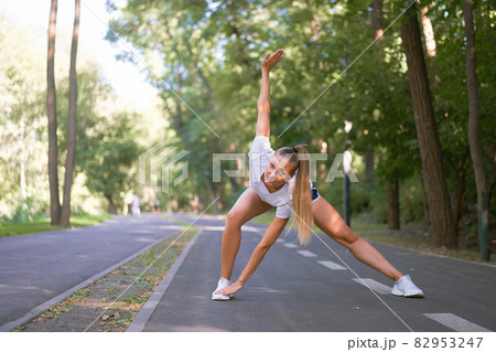 Woman runner stretching legs before exercising summer park morning Woman runner stretching legs before exercising summer park morning 82953247