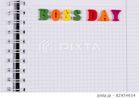National Happy Boss Day. Multicolored colorful letters in a squared exercise book on the table. Bosses Day office greeting card with copy space for text. Close-Up. Top view. View from above 82954634