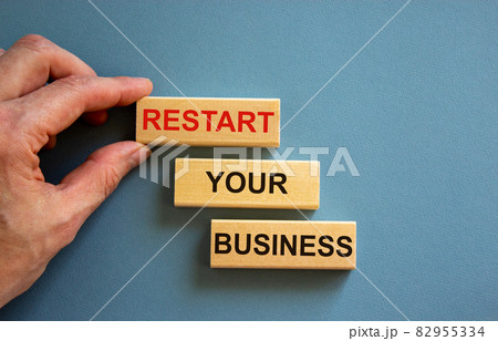 Wooden blocks form the words 'restart your business' on blue background. Male hand. Copy space. Business concept. 82955334