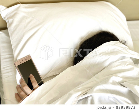 ベッドの中でスマホを置いて寝落ちする人 82959973