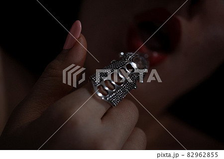 Gothic style shot of a woman with claw rings touching lips Gothic style shot of a woman with claw rings touching lips 82962855