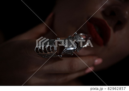 Gothic style shot of a woman with claw rings touching lips Gothic style shot of a woman with claw rings touching lips 82962857