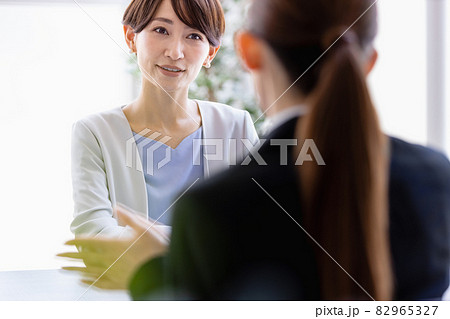 向かい合わせに座っているスーツを着た女性と会話するミドルの女性 向かい合わせに座っているスーツを着た女性と会話するミドルの女性 82965327