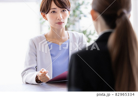 向かい合わせに座っているスーツを着た女性と会話するミドルの女性 向かい合わせに座っているスーツを着た女性と会話するミドルの女性 82965334