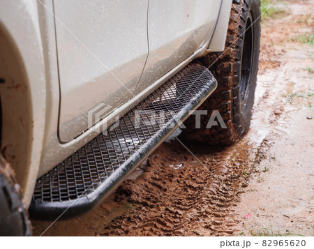 Dirty rear wheel of the off-road 4x4 truck at a countryside rural place in Rainy vibe, 4wd vehicle in rain, Selective focus shallow depth of field 82965620