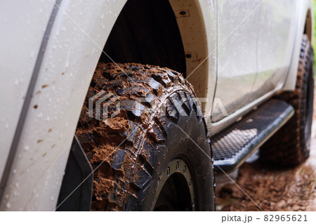 Dirty rear wheel of the off-road 4x4 truck at a countryside rural place in Rainy vibe, 4wd vehicle in rain, Selective focus shallow depth of field 82965621