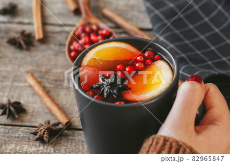 Woman's hands in warm sweater holding a cup of mulled wine 82965847