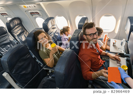 Stewardess in protective gloves giving lunch box to a passenger 82966469
