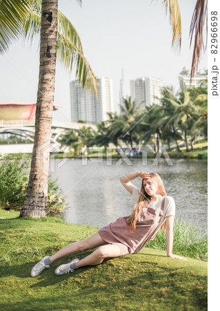 Pretty girl in casual clothing sitting the grass in the park. Long blond hair. Trendy casual summer or spring outfit Pretty girl in casual clothing sitting the grass in the park. Long blond hair. Trendy casual summer or spring outfit 82966698