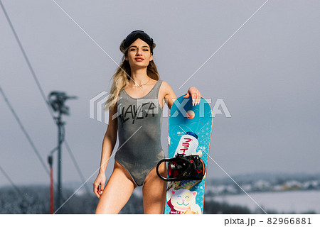Attractive woman dressed in swimsuit with snowboard on the slope Attractive woman dressed in swimsuit with snowboard on the slope 82966881