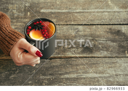 Woman's hands in warm sweater holding a cup of mulled wine Woman's hands in warm sweater holding a cup of mulled wine 82966933