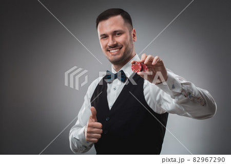 Young man in shirt and waistcoat shows his poker chips, studio shot 82967290