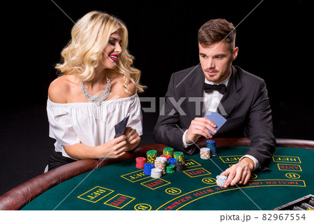 View of young, confident, man with the lady while he's playing poker game. View of young, confident, man with the lady while he's playing poker game. 82967554