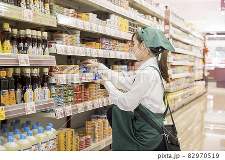 スーパーで商品管理をするマウスシールドをした女性従業員 82970519