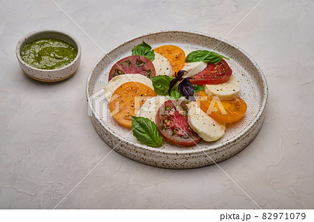 Caprese salad with red and yellow tomatoes, pesto, basil and mozzarella cheese Caprese salad with red and yellow tomatoes, pesto, basil and mozzarella cheese 82971079