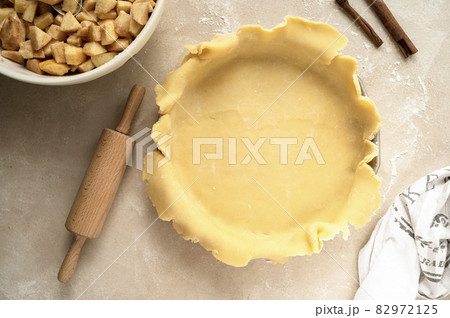 Tart dough or shortcrust pastry, in ceramic tart pan. Baking an apple rustic pie. Top view. 82972125