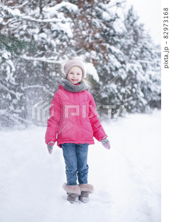 Little girl in a bright jacket plays in the winter forest Little girl in a bright jacket plays in the winter forest 82973168