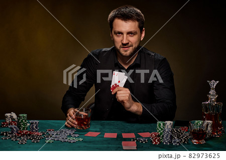 Bearded casino player man playing poker on green table Bearded casino player man playing poker on green table 82973625