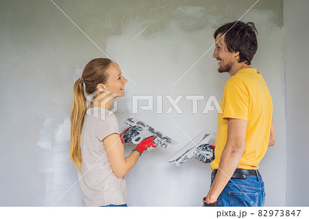 A man and a woman are plastering the walls of the house. DIY home renovation A man and a woman are plastering the walls of the house. DIY home renovation 82973847