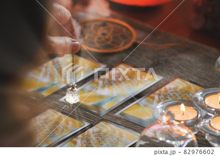 Hand with pendulum over tarot cards 82976602